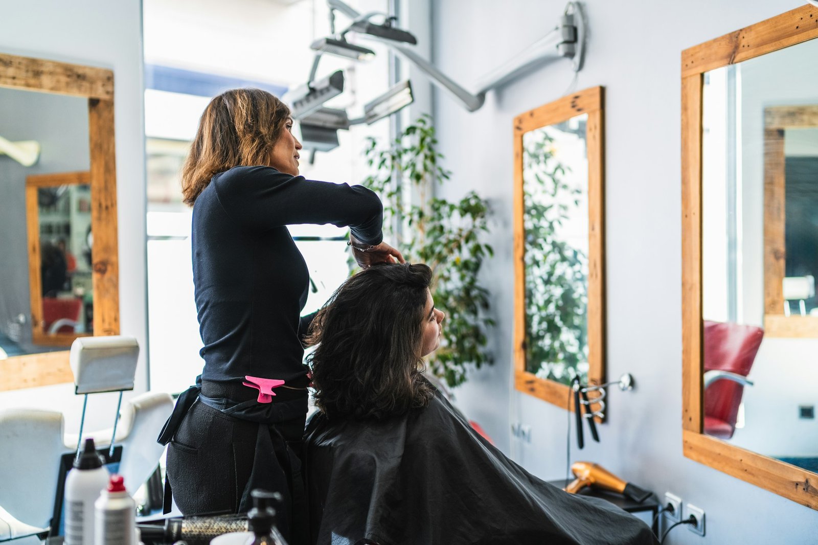 A woman is getting her hair cut by customer woman in a salon